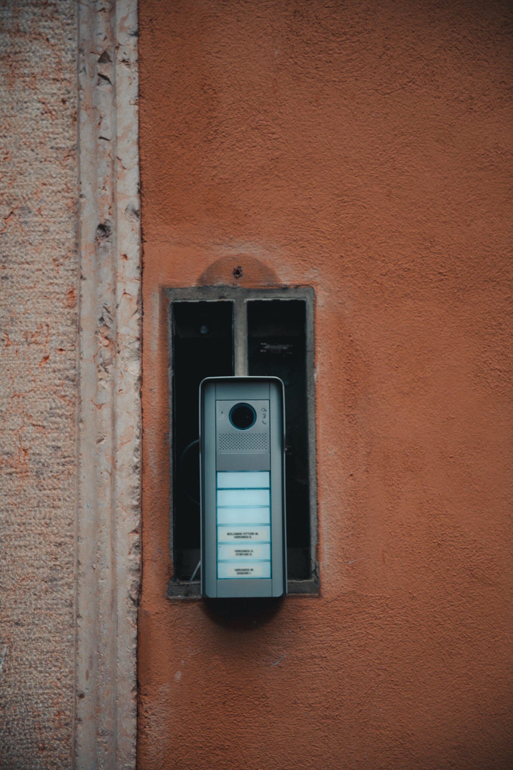 A sleek, modern intercom installed on a rustic, textured wall, blending past and present.